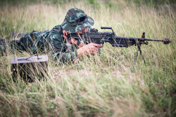 istock Sniper laying on the grass looking through scope at the target 941417298