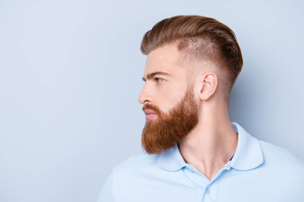 Side view close up portrait of handsome bearded young serious man in polo isolated on copyspace Side view close up portrait of handsome bearded young serious man in polo isolated on copyspace facial hair stock pictures, royalty-free photos & images