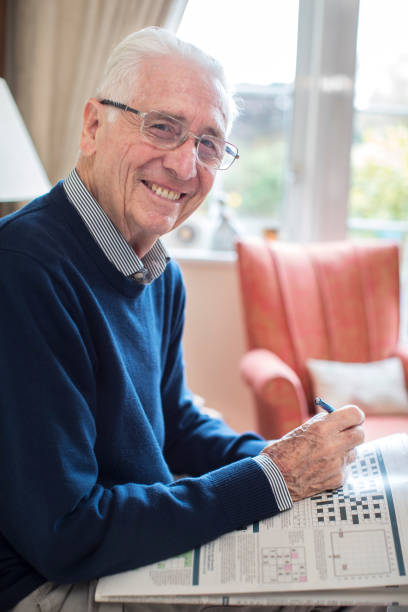 portrait d’un homme senior fait des mots croisés à la maison - mental illness energy people men photos et images de collection