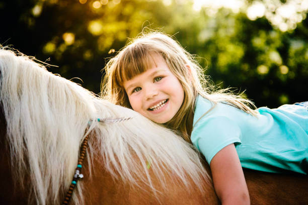 Young girl spending cold winter weekend on family farm, taking care of her brown fluffy pony, hugging him