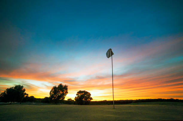 golf-loch-flagge über einen sonnenuntergang himmel - golf golf flag sunset flag stock-fotos und bilder