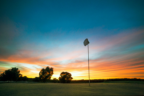 Golf hole flag over a sunset sky