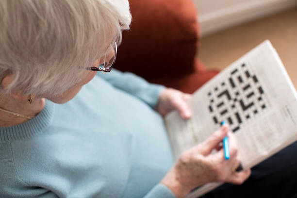 senior mujer haciendo crucigramas en casa - one person lifestyles 80 plus years indoors fotografías e imágenes de stock