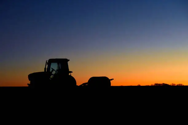 A colorful sky behind a resting tractor