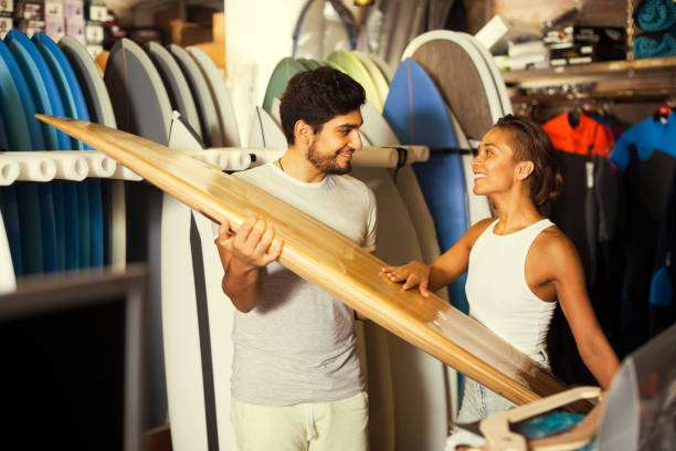 male and female surfers holding surfboard