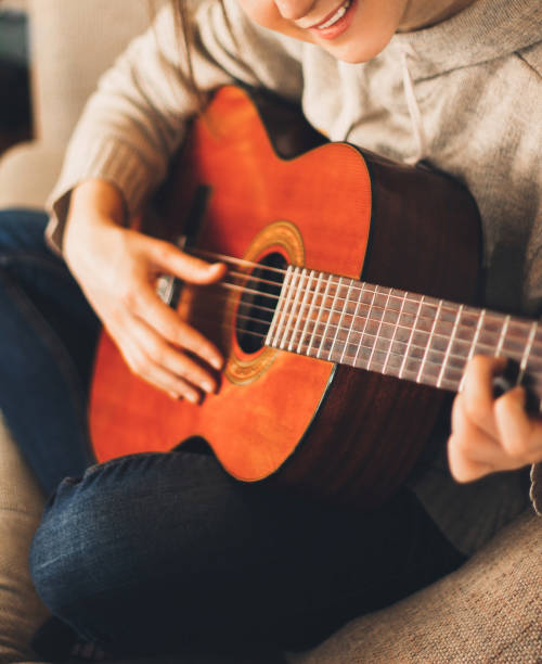 istock Young woman playing guitar at home 941439096