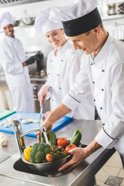 istock smiling chef washing vegetables at restaurant kitchen 941439386