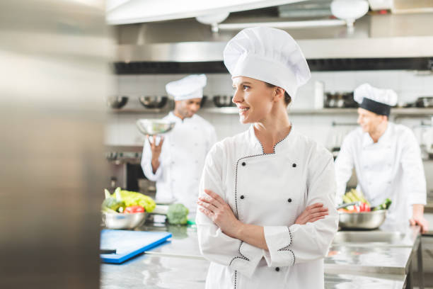 istock smiling chef standing with crossed arms and looking away at restaurant kitchen 941439524