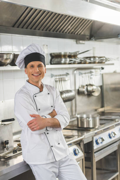 istock smiling chef standing with crossed arms and looking at camera at restaurant kitchen 941439618