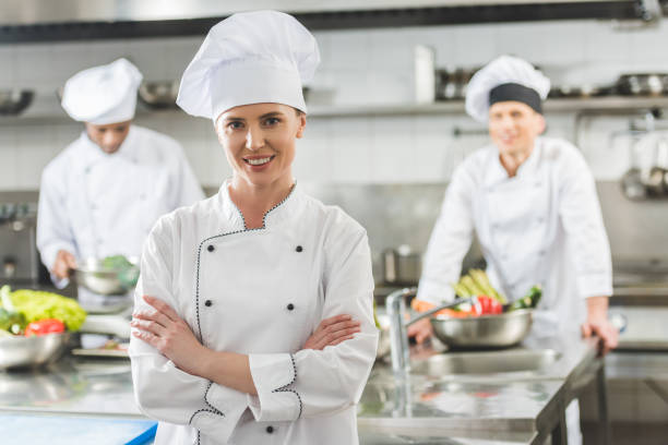 istock smiling chef standing with crossed arms and looking at camera at restaurant kitchen 941439706