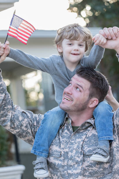 istock Excited boy sits on his soldier dad's shoulders 941439778