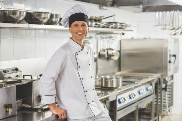 istock smiling chef leaning on table and looking at camera at restaurant kitchen 941440268