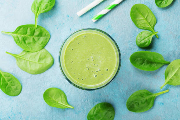 frullato di spinaci verdi sulla vista dall'alto del tavolo blu. detox e cibo dietetico per la colazione. - juice glass healthy eating healthy lifestyle foto e immagini stock