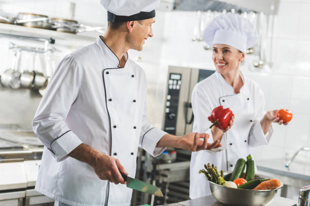 istock smiling chef giving red bell pepper to colleague at restaurant kitchen 941440586