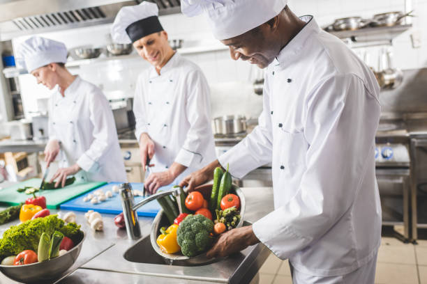 istock smiling african american chef washing vegetables at restaurant kitchen 941442722