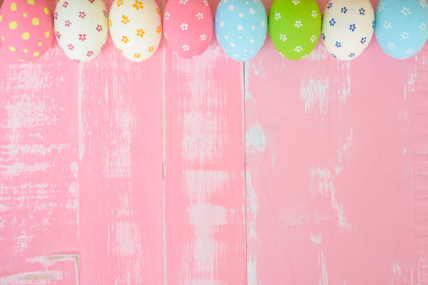 istock Happy easter! Row Easter eggs with colorful paper flowers on bright pink wooden background. 941443006