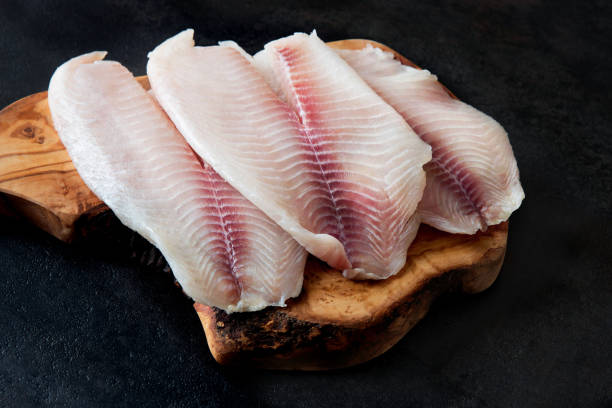 istock Fresh fish fillet on the chopping board on a black background 941443190