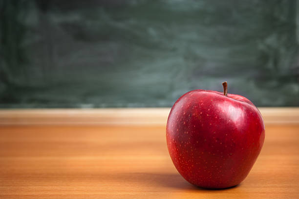 A red Apple on a teachers desk from a student stock photo
