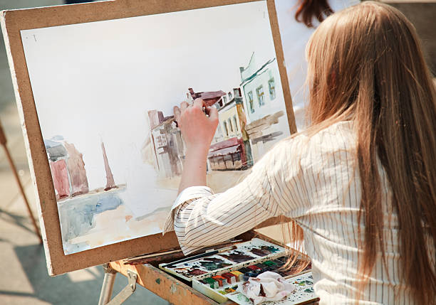 Woman painting a portrait of a city street in watercolors stock photo