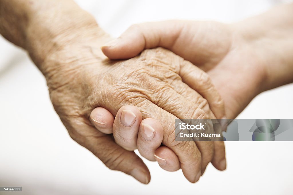 adult helping senior in hospital  Hands Clasped Stock Photo
