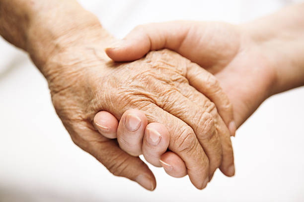 adult helping senior in hospital stock photo