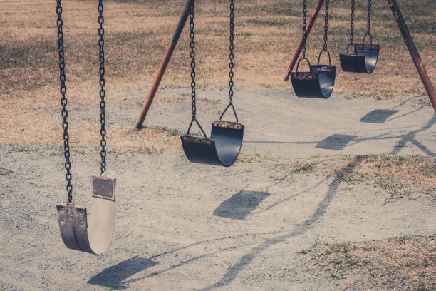 swings on old playground  - vintage outdoor playground - swing playground empty abandoned imagens e fotografias de stock