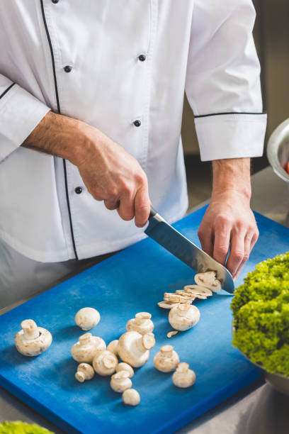 istock cropped image of chef cutting mushrooms at restaurant kitchen 941451408