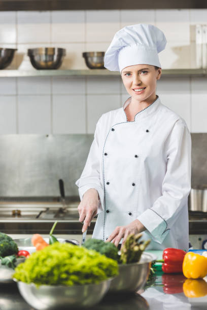 istock attractive chef cutting vegetables at restaurant kitchen and looking at camera 941456478