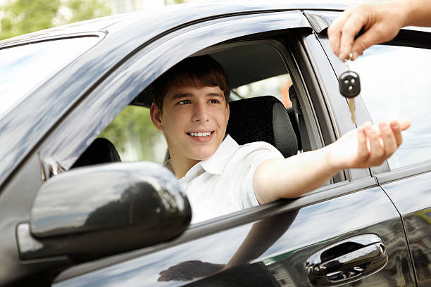 Happy young boy get handed keys to the car stock photo