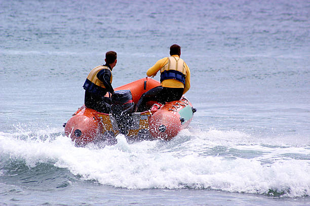 An image of men in raft riding over waves stock photo