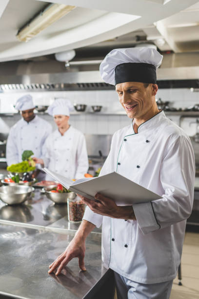 istock smiling chef reading recipe at restaurant kitchen 941463094