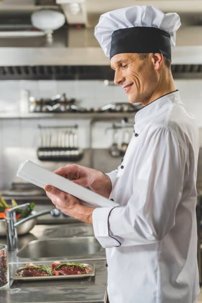 istock side view of handsome chef reading recipe book at restaurant kitchen 941463884