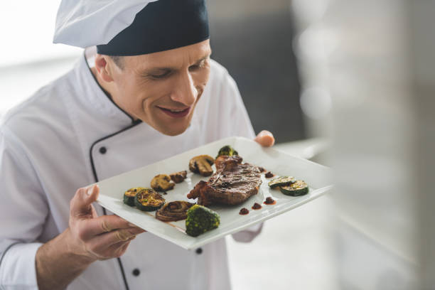 istock handsome chef sniffing cooked steak with vegetables at restaurant kitchen 941469232