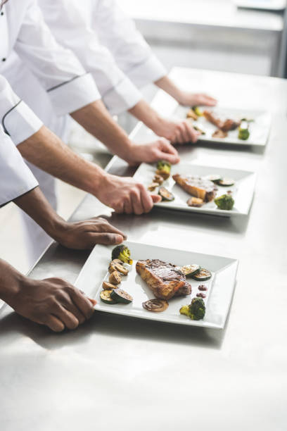 istock cropped image of multiethnic chefs with plates with steaks at restaurant kitchen 941469550