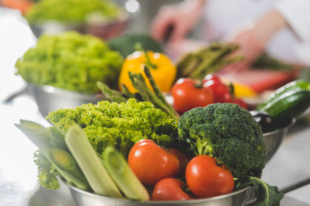 istock cropped image of chef cooking at restaurant kitchen with ripe vegetables on foreground 941473744