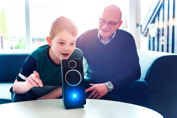 niño habla a ayudante digital mientras que su abuelo le miran - personal data assistant fotografías e imágenes de stock