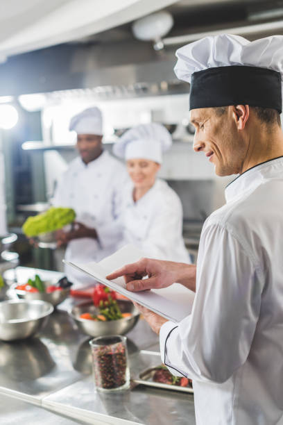 istock chef pointing on recipe book at restaurant kitchen 941477274