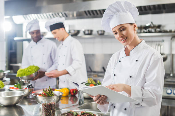 istock attractive chef reading recipe in recipe book at restaurant kitchen 941477436