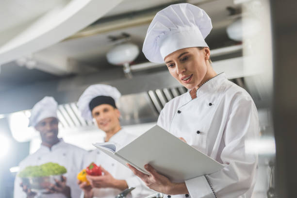 istock attractive chef reading recipe at restaurant kitchen 941477490