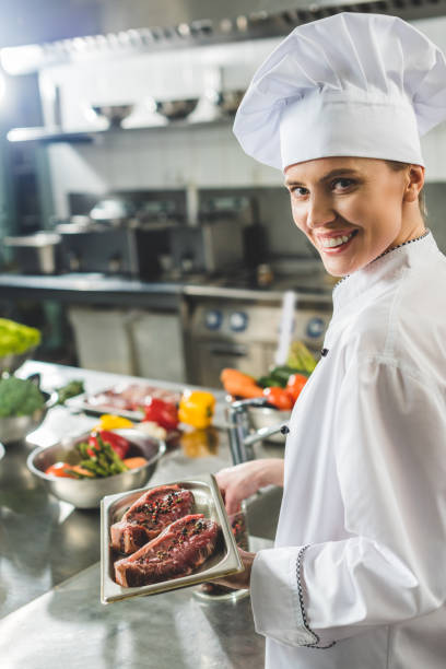 istock attractive chef holding tray with raw meat at restaurant kitchen 941477596
