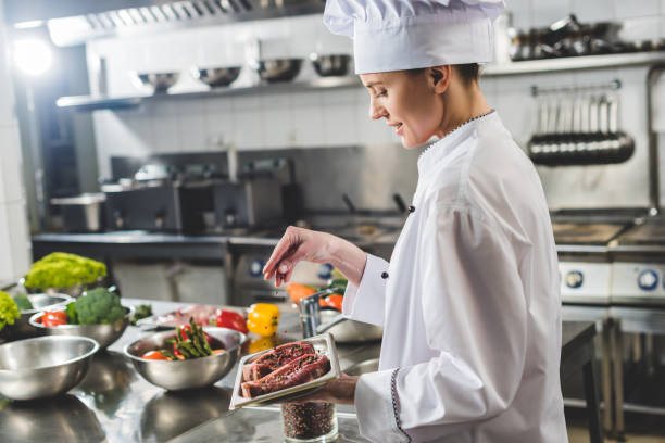 istock attractive chef adding herbs to raw steaks at restaurant kitchen 941477864