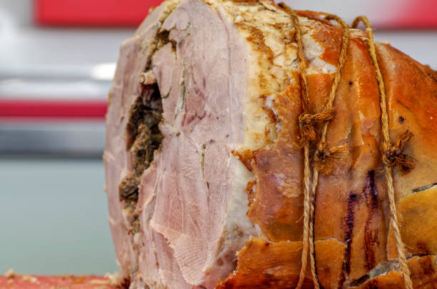 baked ham on a wooden stand, a knife and orange juice in a glass