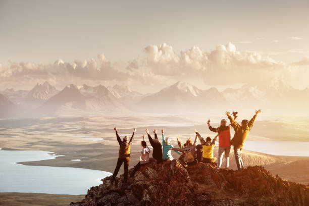 Big group of people success mountain top Big group of people having fun in success pose with raised arms on mountain top against sunset lakes and mountains. Travel, adventure or expedition concept horizon over land photos stock pictures, royalty-free photos & images