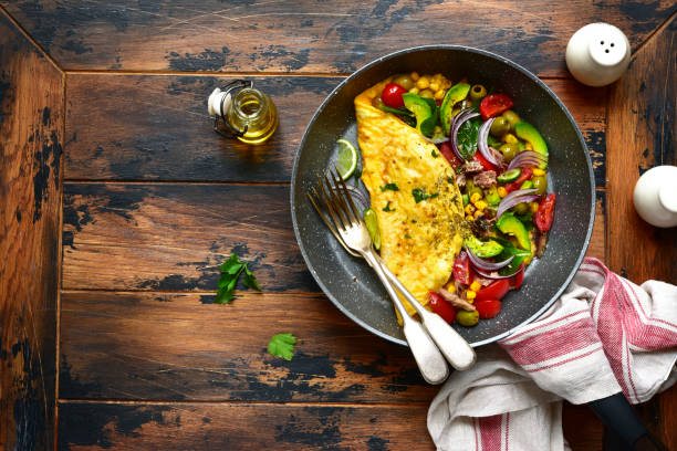 Omelette stuffed with vegetables Omelette stuffed with vegetables in a black skillet for a breakfast over dark wooden background.Top view with copy space. paleo diet photos stock pictures, royalty-free photos & images