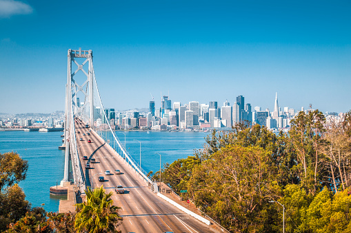 Classic panoramic view of San Francisco skyline with famous Oakland Bay Bridge illuminated on a beautiful sunny day with blue sky in summer, San Francisco Bay Area, California, USA