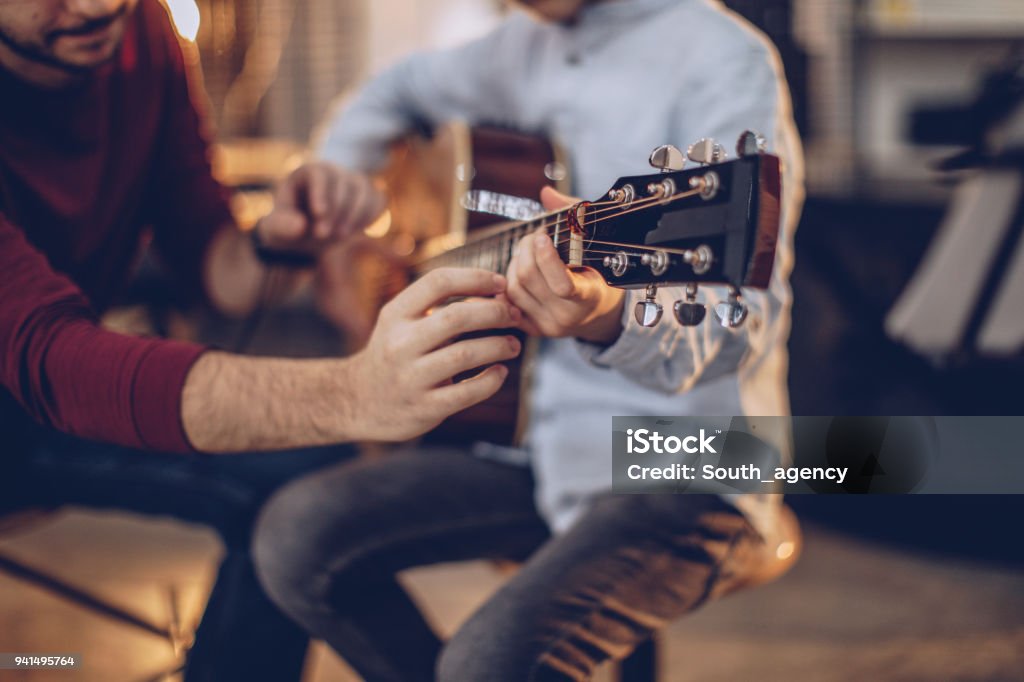 First guitar class Two people, man guitar teacher working with little boy on guitar lessons. Music Stock Photo