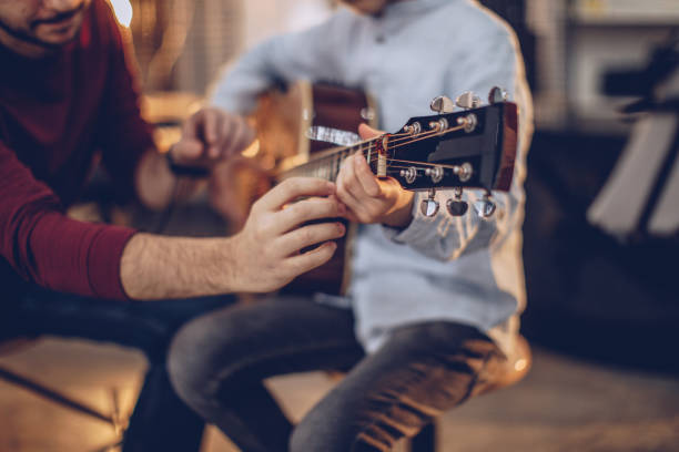 First guitar class Two people, man guitar teacher working with little boy on guitar lessons. music theory stock pictures, royalty-free photos & images