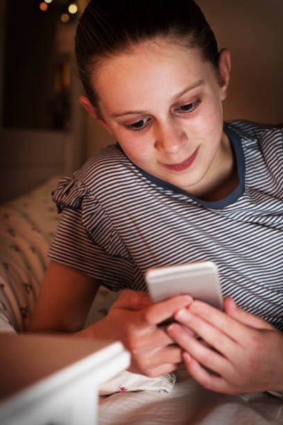 istock Young Girl Checking Text Messages Lying On Bed At Night 941503956