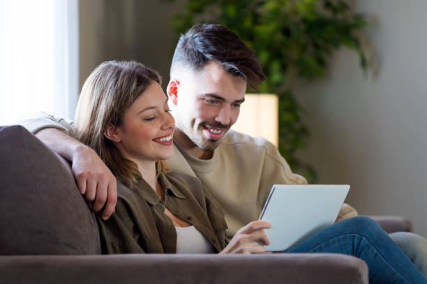 istock Beautiful young smiling couple using their digital tablet at home. 941504248