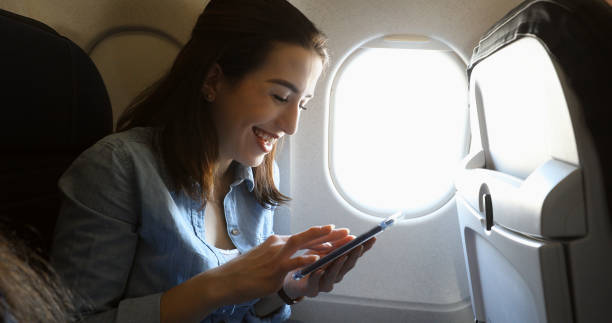 istock Happy woman uses smart phone on airplane 941504566